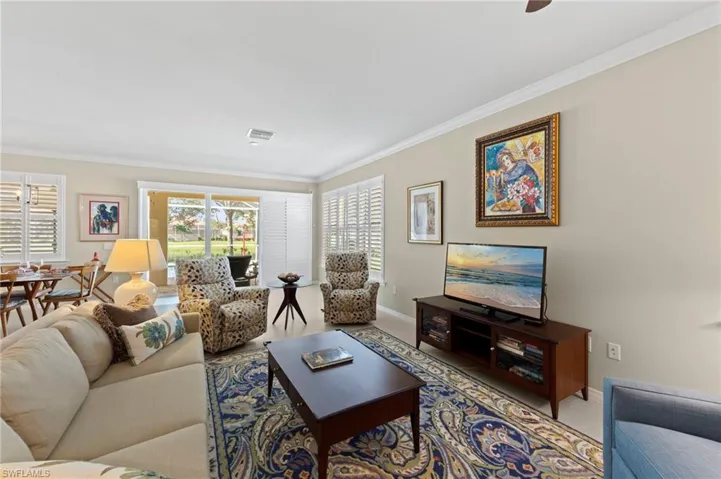 Carpeted living area with ornamental molding and baseboards