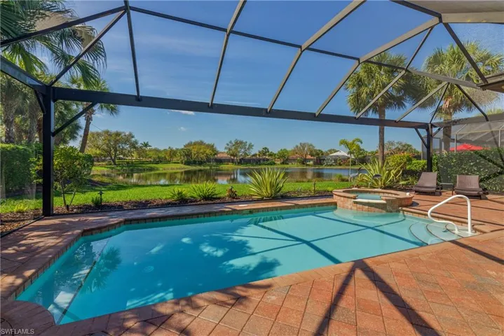 View of pool with a water view, a patio area, a pool with connected hot tub, and a lanai