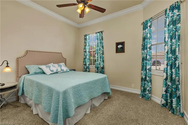 Carpeted bedroom with a ceiling fan, baseboards, and crown molding