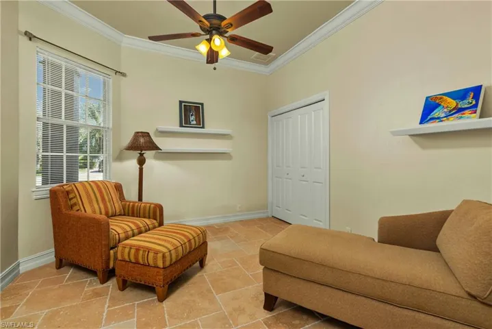 Sitting room featuring stone tile flooring, crown molding, and baseboards