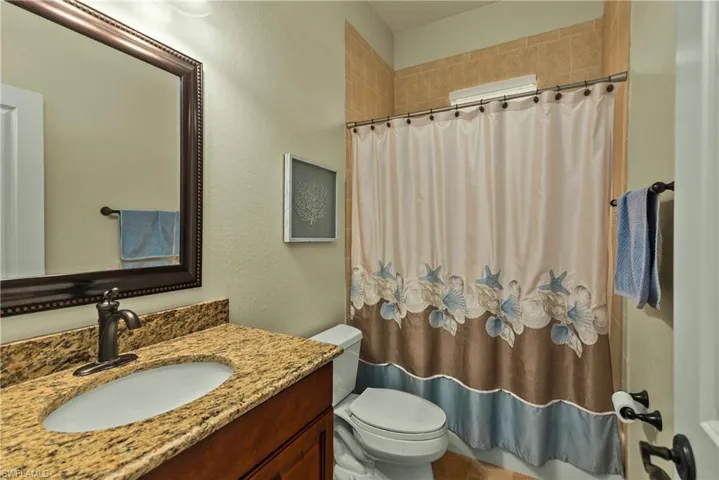 Full bathroom with toilet, a shower with curtain, and vanity