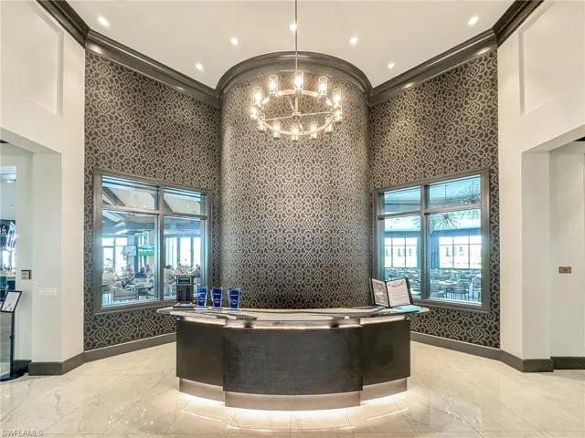 Welcome area featuring a high ceiling, suspended lighting, wallpapered walls, and ornamental molding