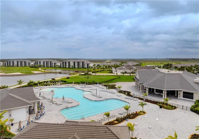 Community pool with a patio, view of golf course, and a water view