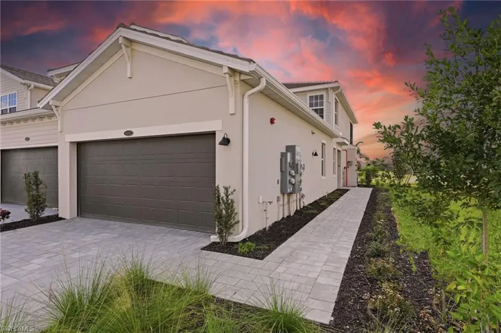 View of side of home featuring stucco siding, an attached garage, and driveway