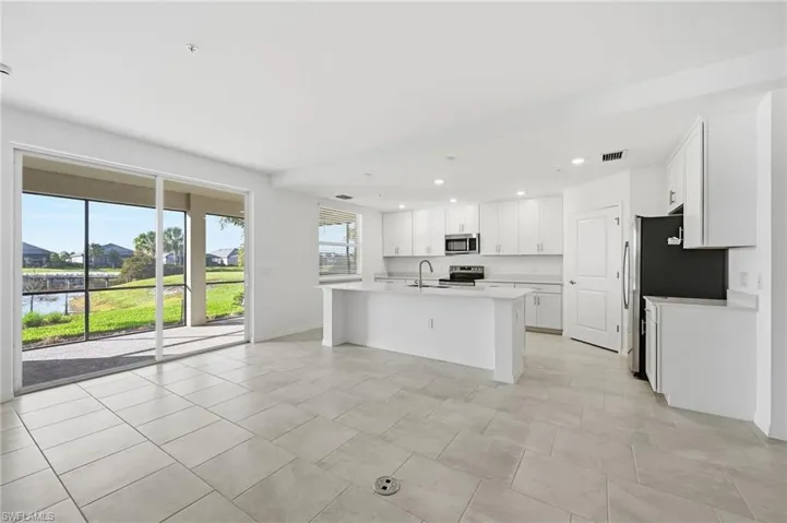 Kitchen with white cabinetry, a center island with sink, stainless steel appliances, recessed lighting, and light stone countertops