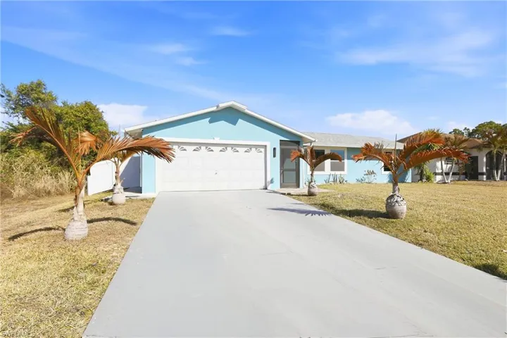 Ranch-style home with stucco siding, driveway, a front lawn, and a garage