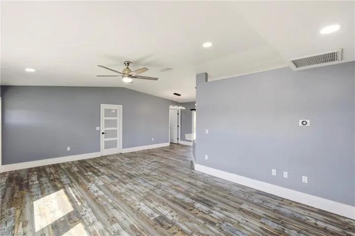Spare room featuring lofted ceiling, a ceiling fan, wood finished floors, and recessed lighting