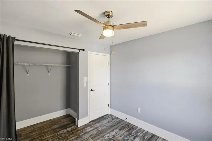 Unfurnished bedroom with dark wood finished floors, a closet, and a ceiling fan