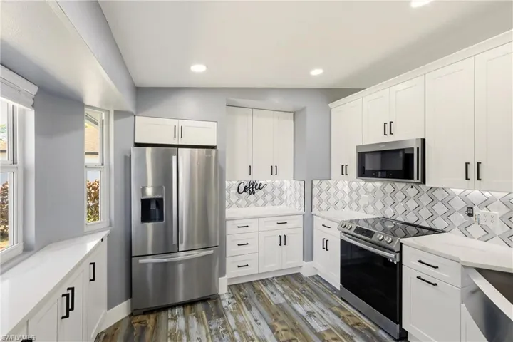 Kitchen featuring stainless steel appliances, white cabinets, light stone counters, healthy amount of natural light, and recessed lighting