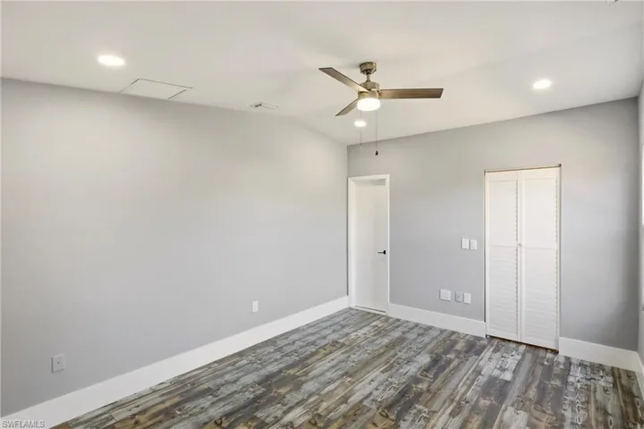 Unfurnished bedroom with recessed lighting, dark wood-type flooring, a closet, ceiling fan, and vaulted ceiling