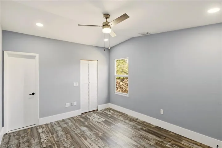 Unfurnished bedroom with recessed lighting, wood finished floors, a ceiling fan, a closet, and lofted ceiling