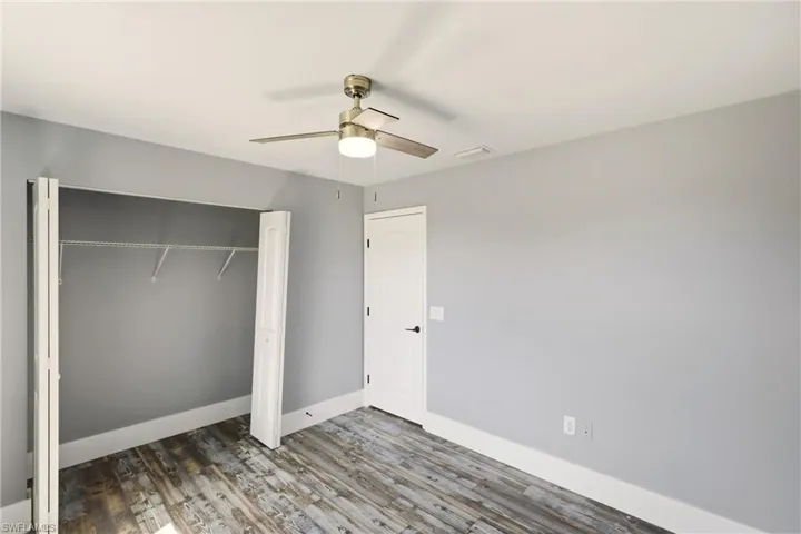 Unfurnished bedroom featuring a closet, wood finished floors, and a ceiling fan