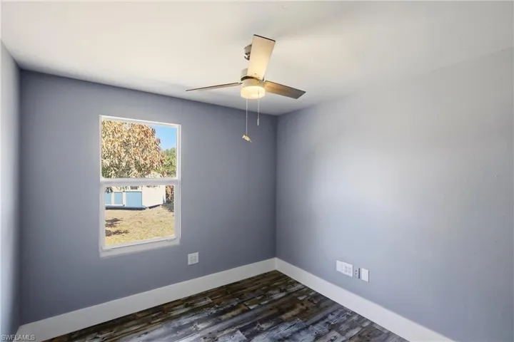 Unfurnished room with dark wood finished floors and ceiling fan