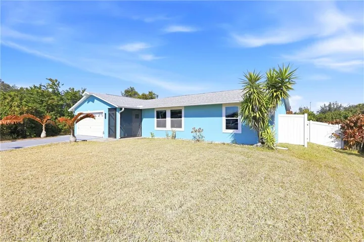 Ranch-style house featuring stucco siding, an attached garage, driveway, and a gate