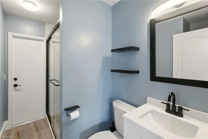 Full bathroom with a shower stall, vanity, and light wood-style floors
