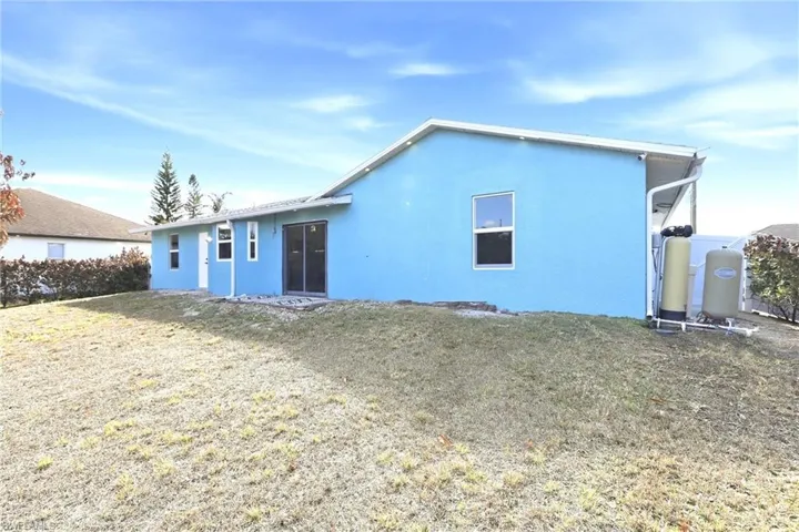 Rear view of property with stucco siding and a lawn