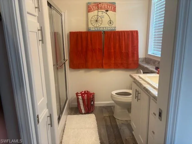 Bathroom with vanity, a shower stall, and dark wood-type flooring
