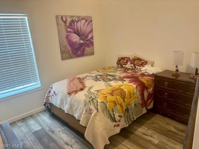Bedroom with dark wood-style floors and multiple windows