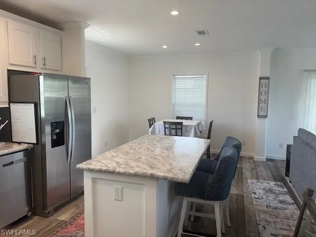 Kitchen with a kitchen bar, appliances with stainless steel finishes, recessed lighting, dark wood finished floors, and white cabinets