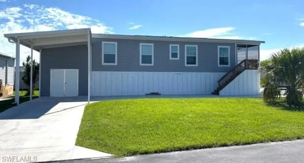 View of front of home featuring stairs, a front lawn, and concrete driveway