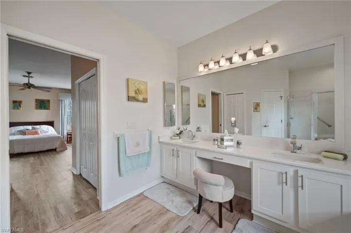 Bathroom featuring ceiling fan, vanity, walk in shower, and hardwood / wood-style flooring