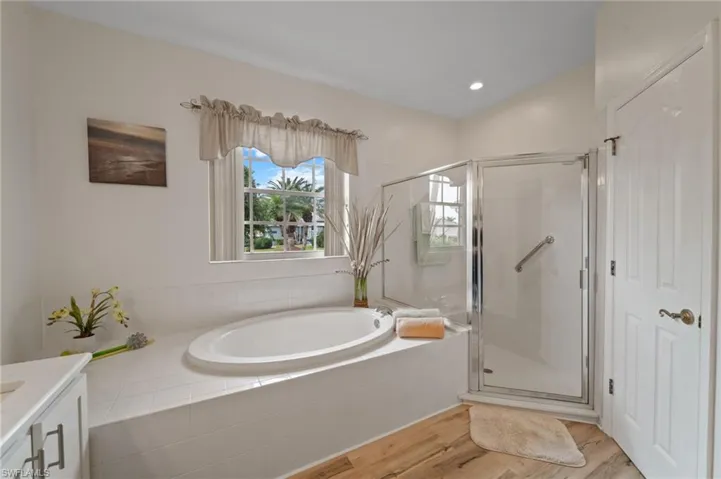 Bathroom with vanity, wood-type flooring, and plus walk in shower