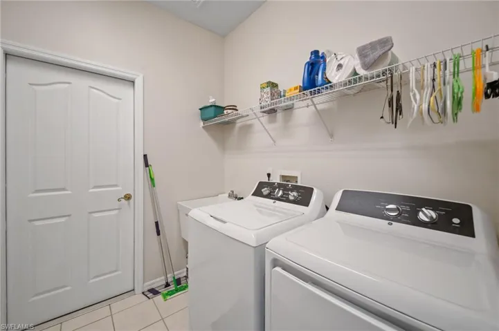 Laundry room with light tile patterned flooring and separate washer and dryer