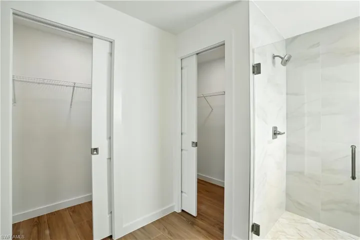 Full bathroom with a spacious closet, a marble finish shower, and light wood finished floors