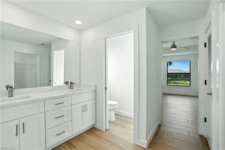 Full bathroom with double vanity, light wood finished floors, ceiling fan, and recessed lighting