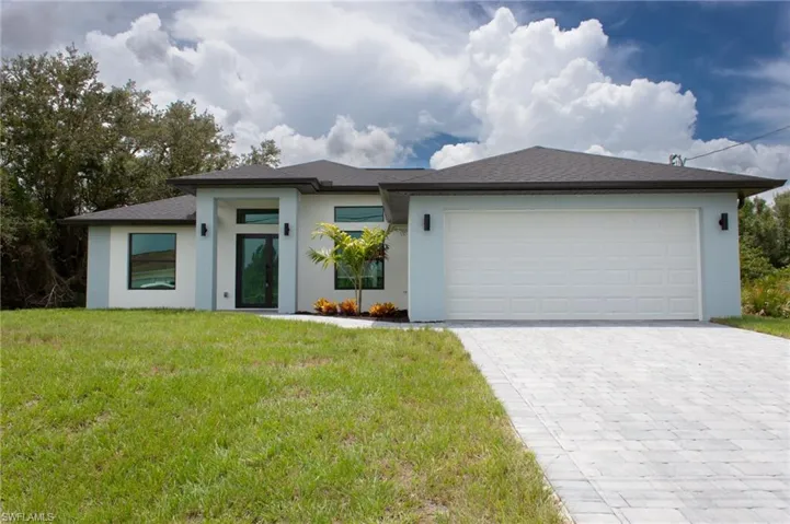 View of front of home featuring decorative driveway, a front lawn, a garage, stucco siding, and roof with shingles