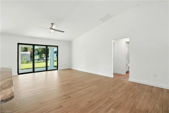 Unfurnished room featuring ceiling fan, light wood-style flooring, and lofted ceiling