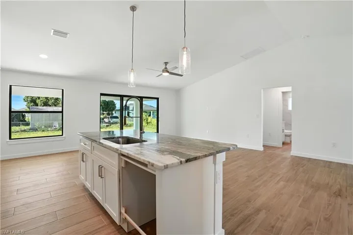 Kitchen featuring light stone countertops, white cabinetry, a ceiling fan, light wood-style floors, and stainless steel dishwasher