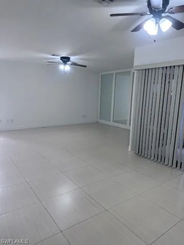 Large-format tile flooring, dual ceiling fans with integrated lighting, and mirrored closet doors with sliding tracks