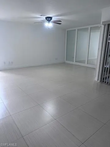 Large-format tile flooring, ceiling-mounted fan with integrated lighting, and full-wall mirrored paneling