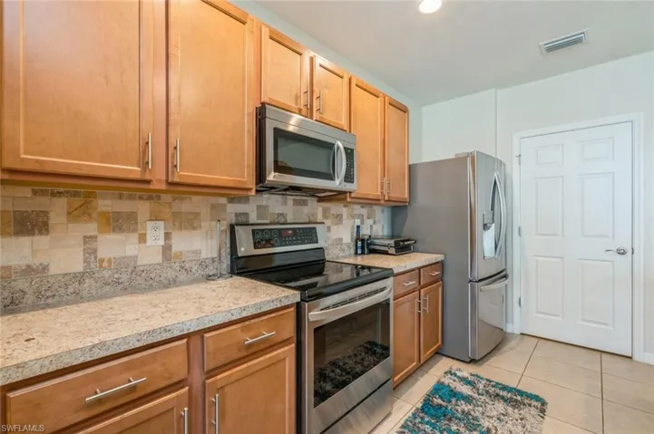 Kitchen with light tile flooring, tasteful backsplash, and appliances with stainless steel finishes