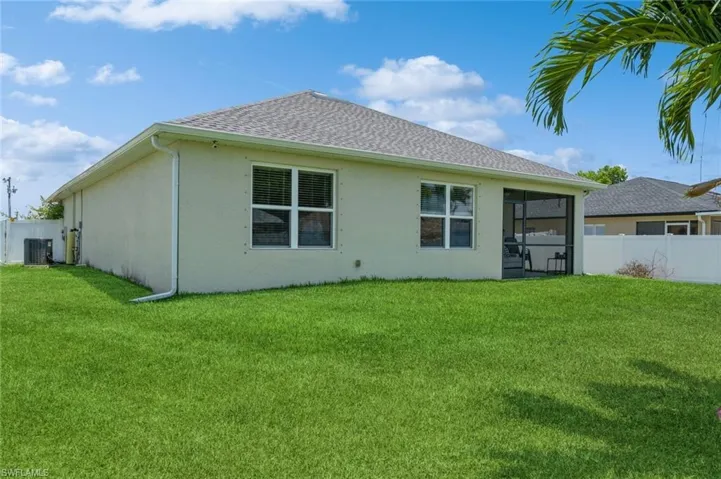 Back of property with central AC and a lawn