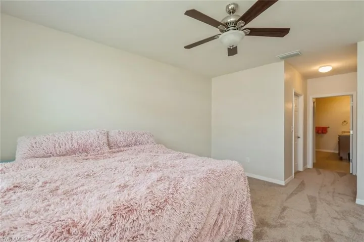 Bedroom with ensuite bath, ceiling fan, and carpet flooring