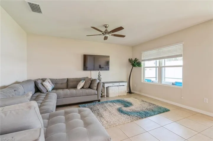Living room with ceiling fan and light tile flooring