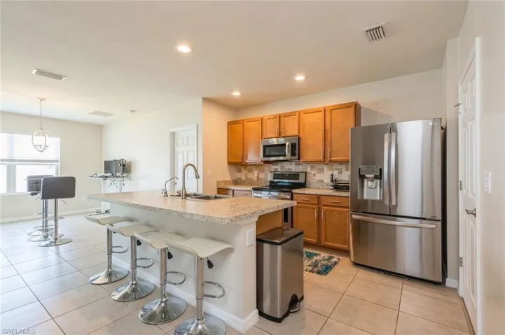 Kitchen with stainless steel appliances, a kitchen island with sink, pendant lighting, sink, and tasteful backsplash