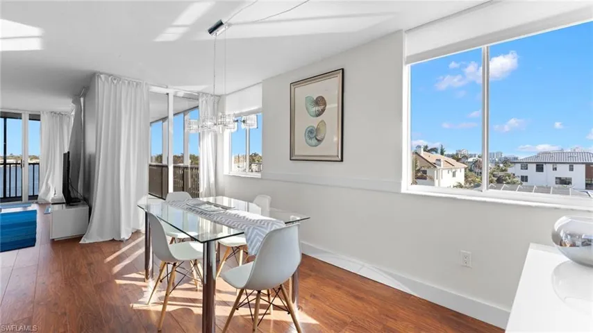 Dining area with a chandelier, dark wood-type flooring, and a healthy amount of sunlight