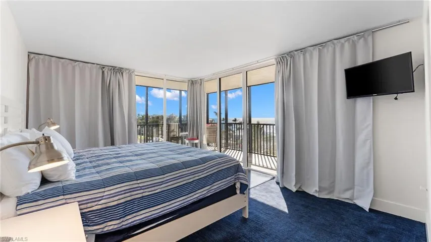 Bedroom featuring access to outside, a wall of windows, and dark colored carpet