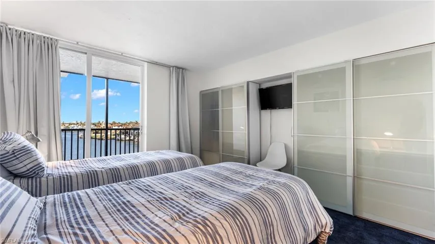 Carpeted bedroom with access to exterior and a water view