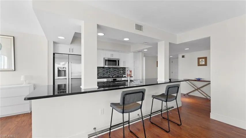 Kitchen with tasteful backsplash, white cabinetry, stainless steel appliances, and dark hardwood / wood-style floors