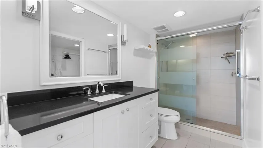 Bathroom featuring tile patterned floors, vanity, a shower with shower door, and toilet