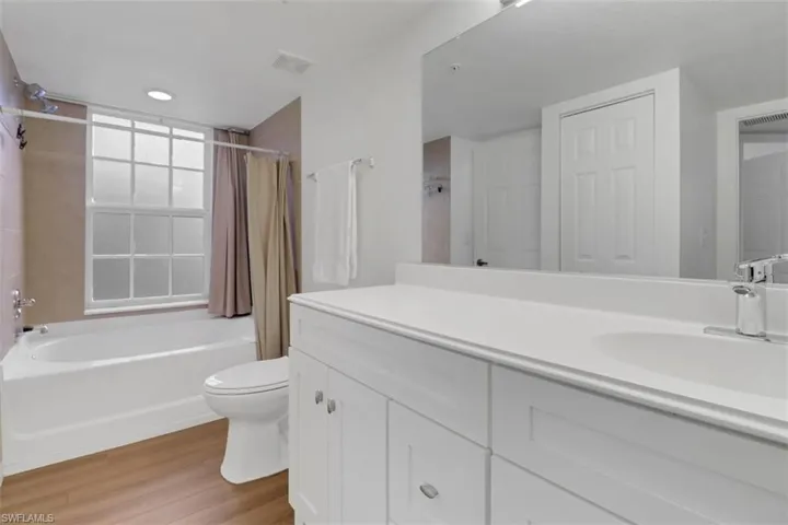 Full bathroom with toilet, vanity, shower / bath combo with shower curtain, and hardwood / wood-style floors