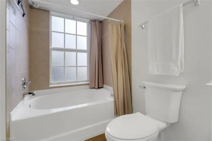 Bathroom with toilet and shower / tub combo with curtain