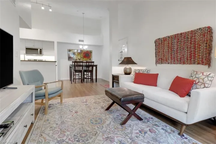 Living room featuring light hardwood / wood-style flooring, a towering ceiling, and a notable chandelier