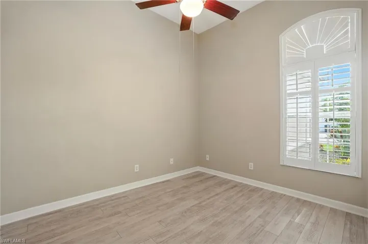 Bedroom with light wood-style floors and a ceiling fan - Virtually Edited Image