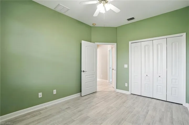 Unfurnished bedroom with light wood-type flooring, a closet, and a ceiling fan - Virtually Edited Image