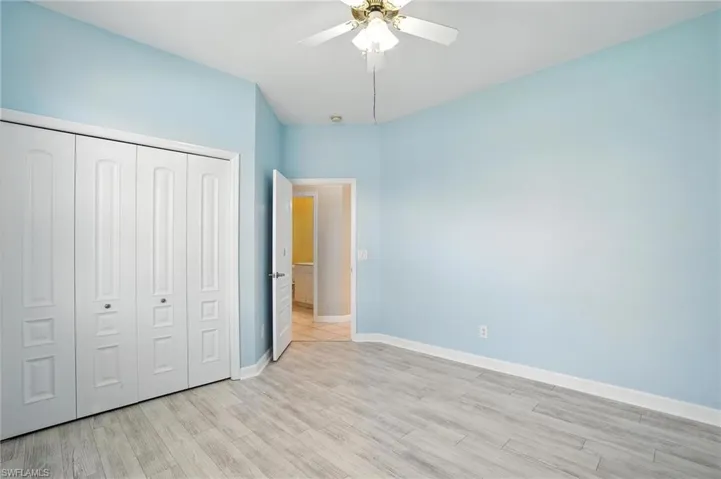 Unfurnished bedroom featuring light wood finished floors, a closet, and a ceiling fan - Virtually Edited Image